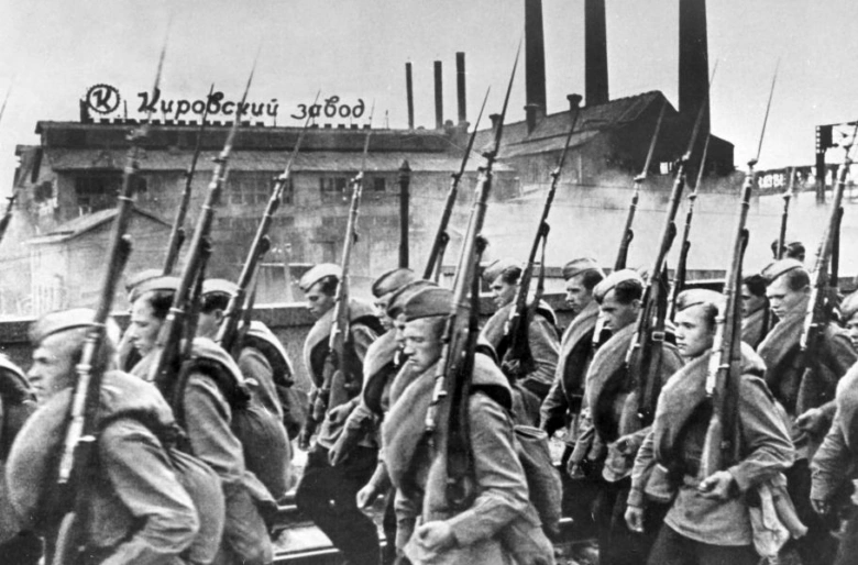 Sovietské vojáci pochodují před továrnou během obléhání Leningradu.