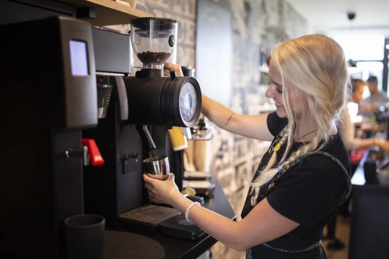 Barista nastavuje mletí kávy v elektrickém mlýnku.