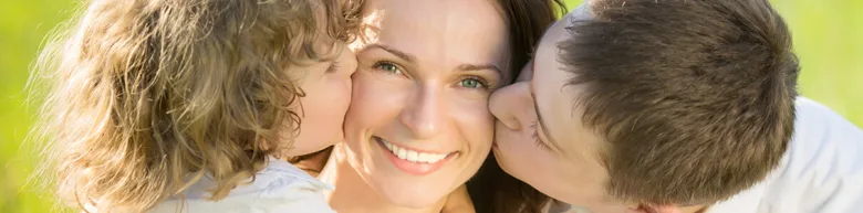 Mother with two children kissing her cheeks