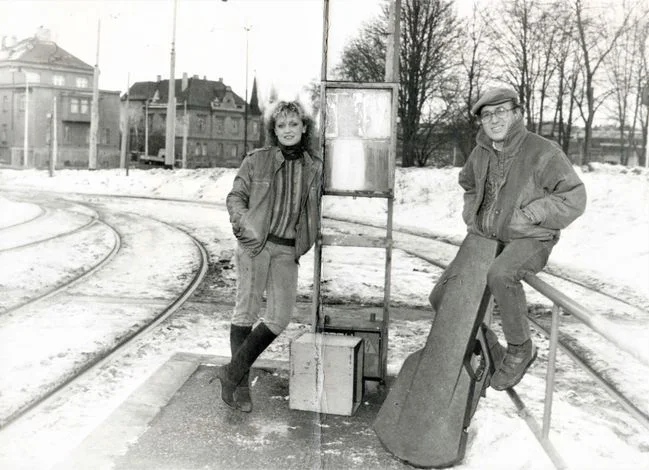 Dvojice stojí u tramvají v zimě na sněhu.