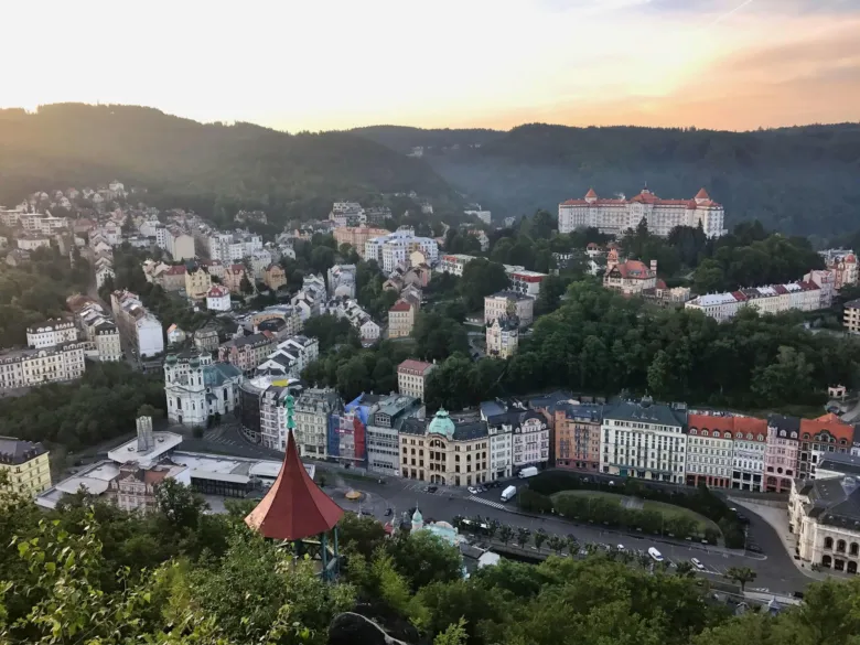 Pohled na město Karlovy Vary s historickými budovami a kopci.