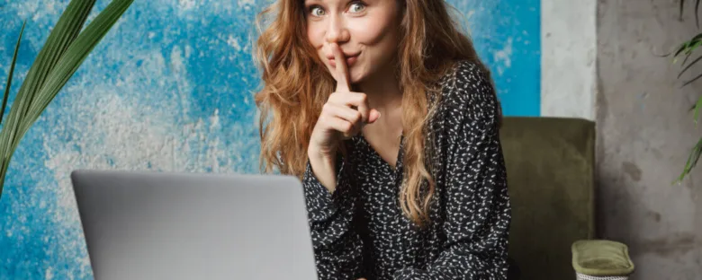 Žena před počítačem s gestem mlčení.