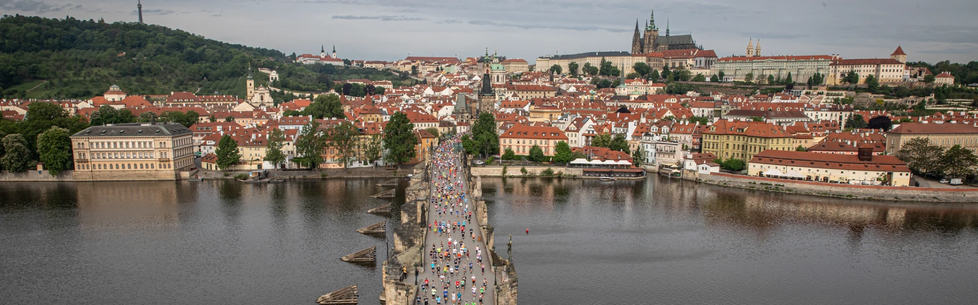 Maraton v Praze na mostě s běžci a historickým městem.