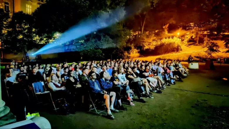 Návštěvníci letního kina v Česku sledují film venku večer.