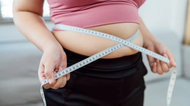 Woman measuring waist with tape measure
