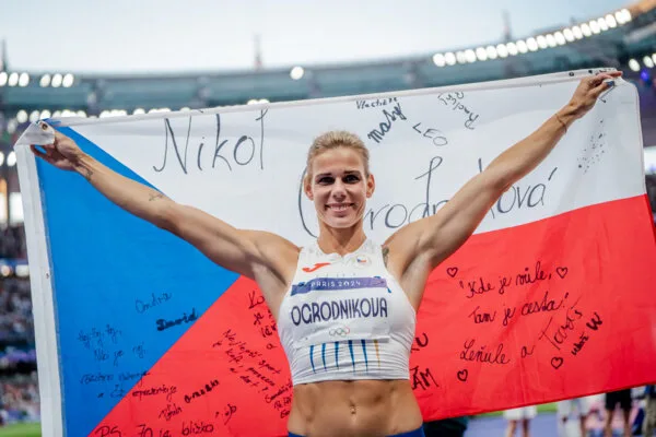 Atletka Nikola Ogrodníková drží českou vlajku na stadionu.