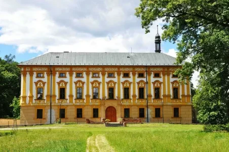 Zelená tráva před žlutým zámkem v obci Albrechtice.