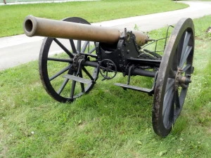 Starý dělostřelecký kanón na kolech vystavený venku.