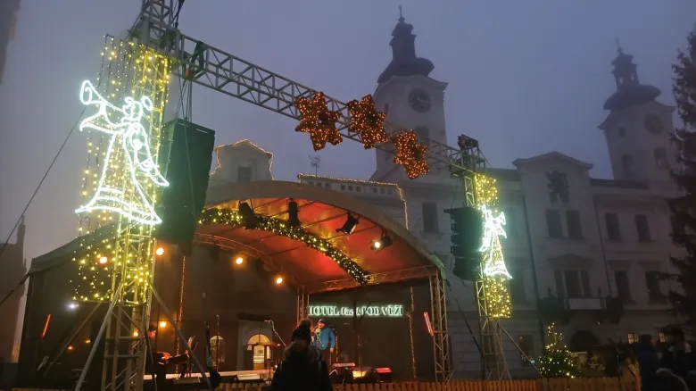 Vánoční trhy v Hradci Králové s osvětleným scénou a historickými budovami na pozadí.