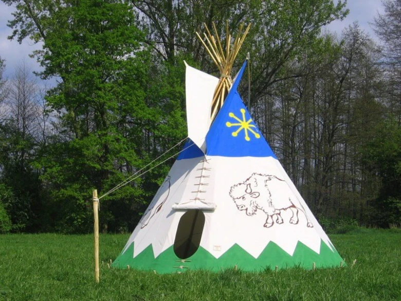 Dětské teepee s kresbami zvířat na trávníku mezi stromy.