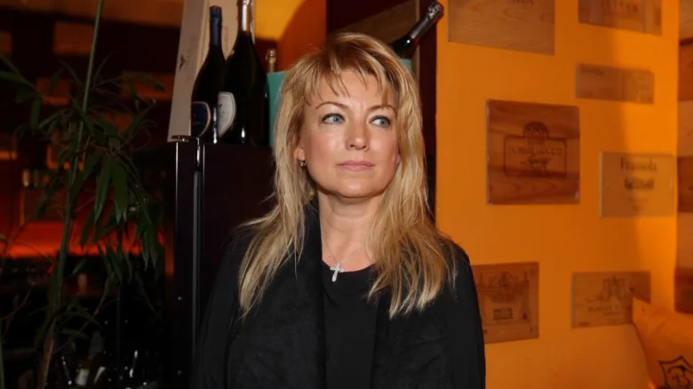 Portrét Evy Vejmělkové v interiéru s vínem na pozadí.