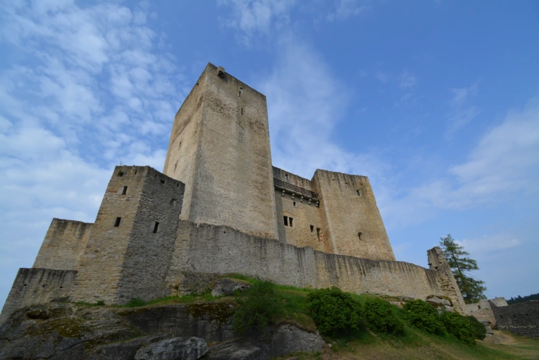 Středověký hrad na skále pod modrou oblohou.