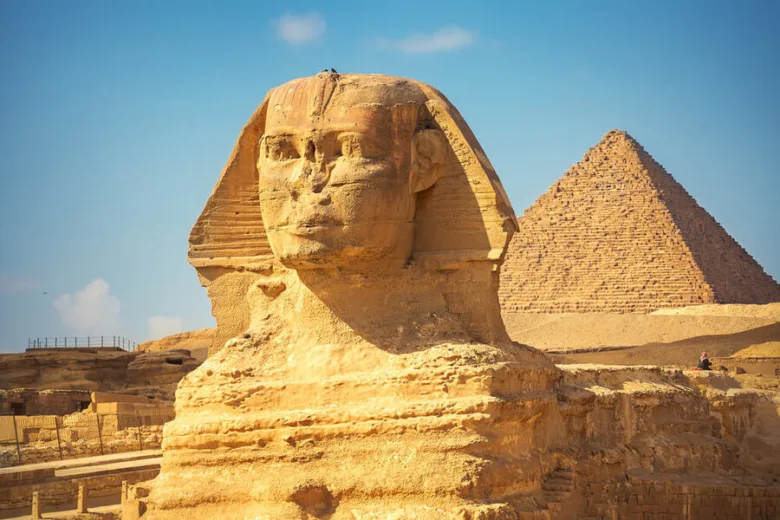 Velká sfinga s pyramidou na pozadí v Egyptě.