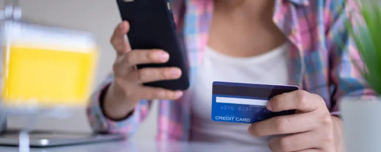 Člověk drží mobilní telefon a kreditní kartu při online půjčce.