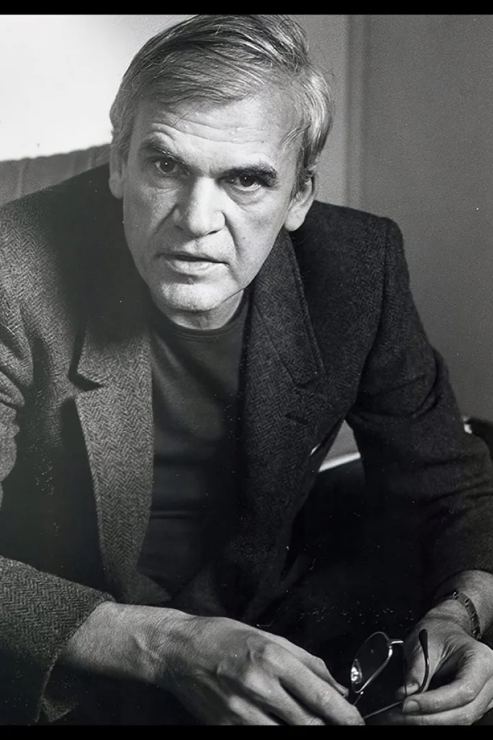 Černobílá fotografie spisovatele Milana Kundery s brýlemi v ruce.