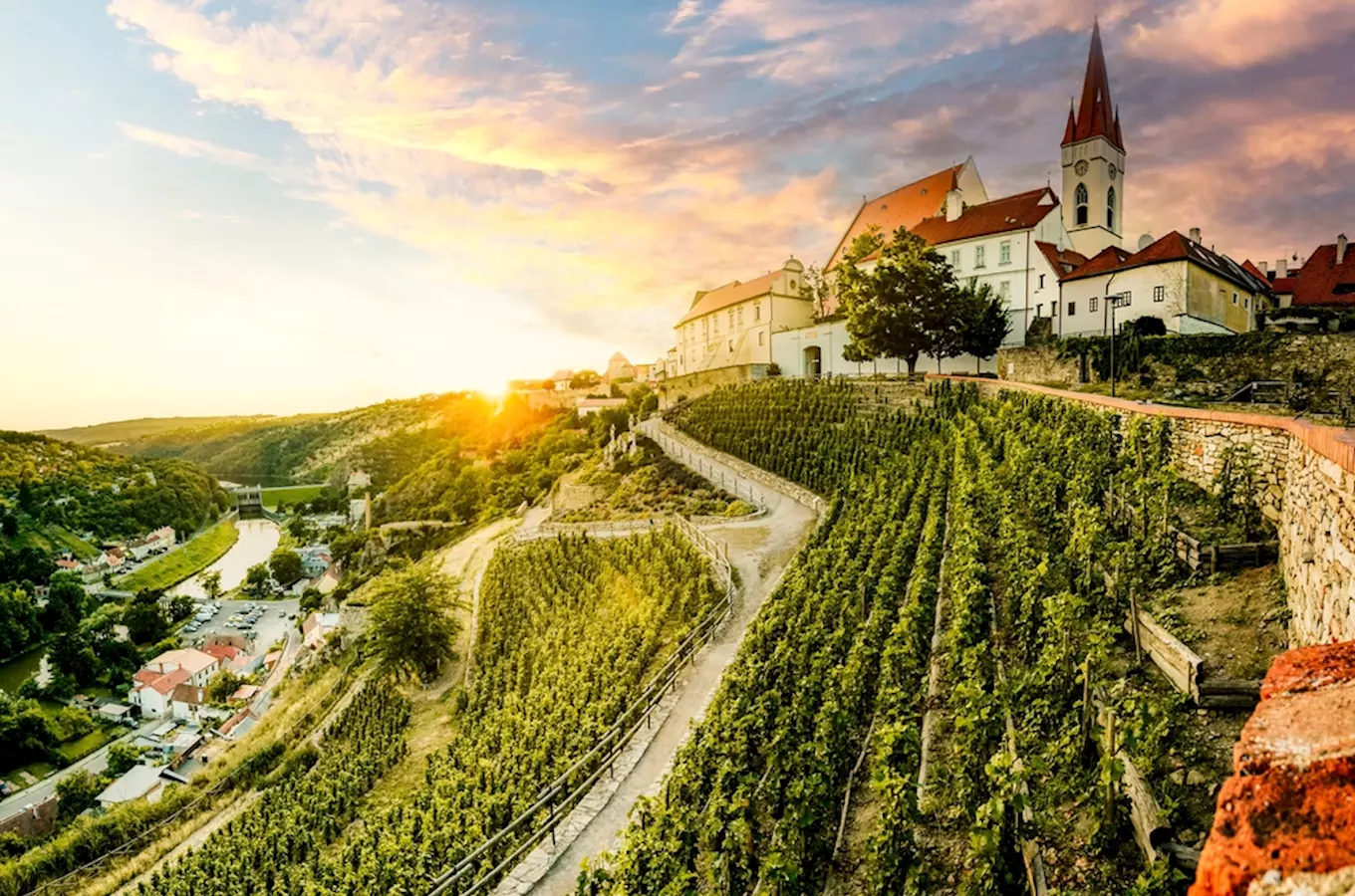Vinné hroje na svahu s kostelem nad řekou ve Znojmě.