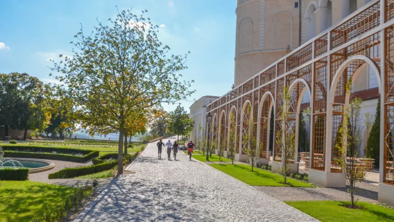 Historic garden walkway with people walking near a large bui