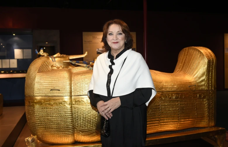 Zlata Adamovská stojí vedle zlatého egyptského sarkofagu v muzeu.