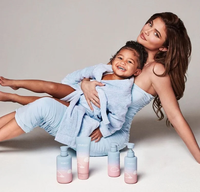 Kylie Jenner s dcerou v modrém oblečení vedle kosmetiky.