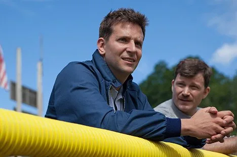 Bradley Cooper v modrém kabátu na venkovním akci.