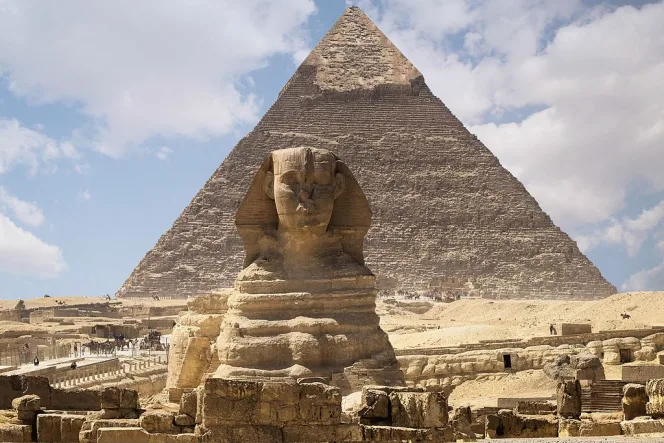 Velká sfinga před Velkou pyramidou v Gíze pod modrou oblohou.