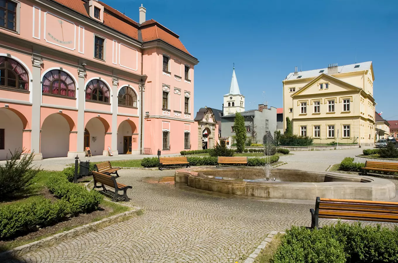 Náměstí s fontánou a historickými budovami ve Valašském Meziříčí.