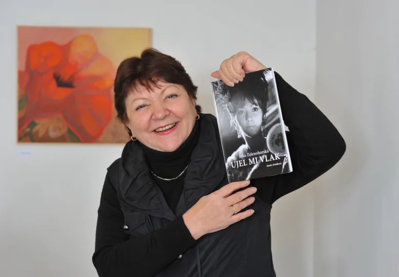 Žena drží knihu s portrétem autorky na obálce.