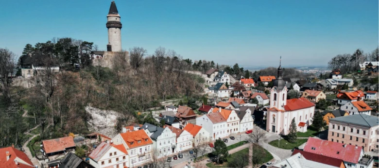Pohled na městečko Štramberk s věží hradu nad barevnými střechami.
