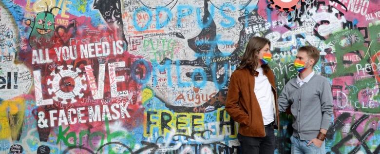 Dva lidé s deštníkovými maskami před grafitovou zdí.