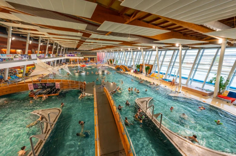 Vnitřní aquapark s bazény a tobogány pro návštěvníky.