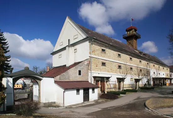 Exteriér hradu Potštejn s věží pod modrou oblohou.
