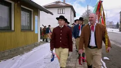 Muži v tradičních kostýmech chodí po sněhu při svátku svaté Barbory.