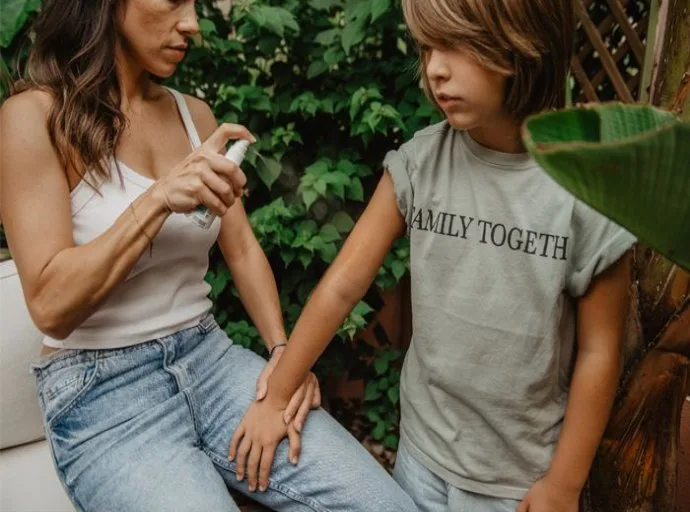 Žena sedí venku s dítětem v tričku FAMILY TOGETHER.