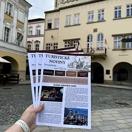 Ruka drží brožuru s turistikou v novém Jičíně na náměstí.