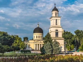 Kostel v Moldavsku s kupolí a zvonovicí na pozadí zelených stromů.