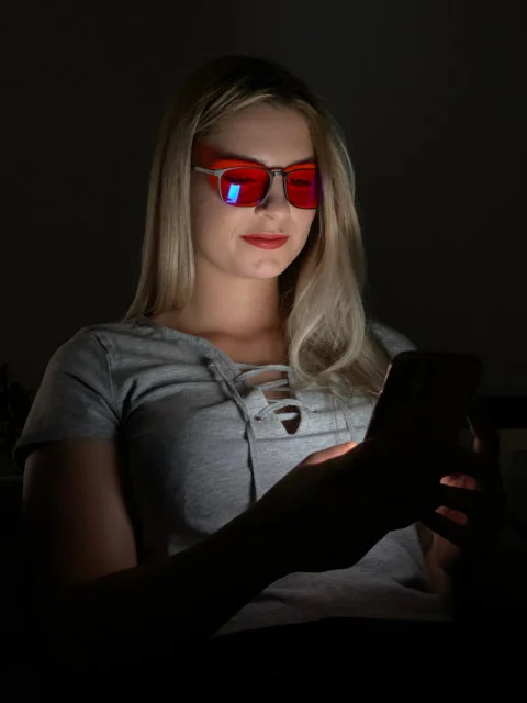 Žena používá chytrý telefon s brýlemi proti modrému světlu.