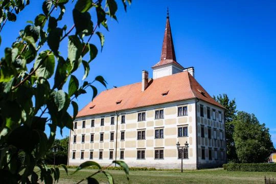 Historická budova v Kroměříži s červenou střechou pod modrou oblohou.