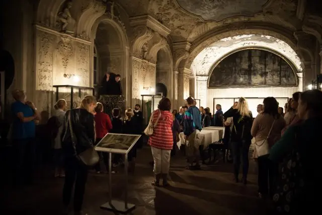 Lidé v historické síni kláštera během kulturní akce.