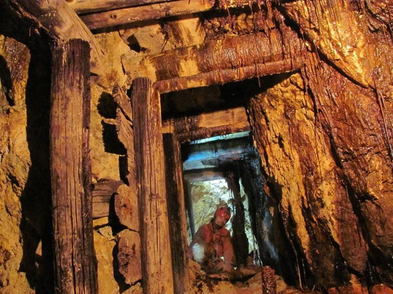 Mining tunnel interior with wooden supports and a person wor