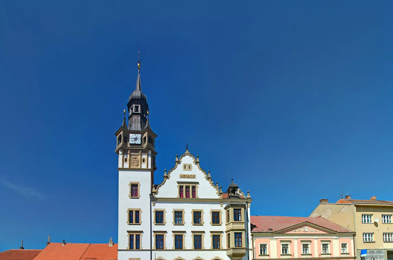 Zámek v Hustopečích s věží a hodinami pod modrou oblohou.