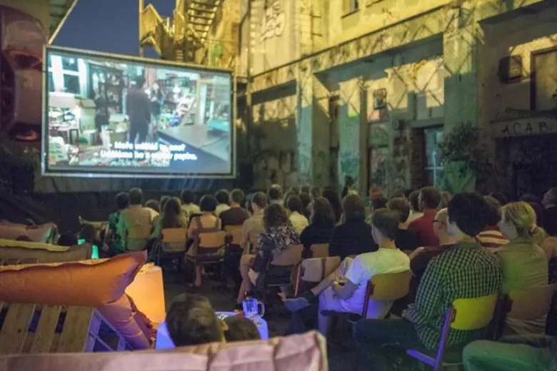 Lidé sedí venku před velkou plátnem při projekci filmu.