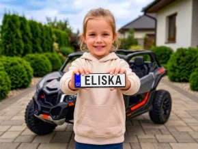 Dětské elektrické auto s dítětem držícím značku.