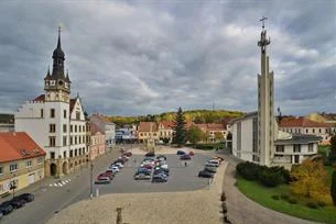 Hlavní náměstí v Hustopečích s kostely a parkovacími místy.
