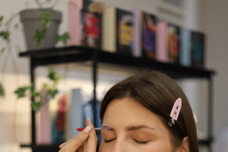 Žena si doma barví obočí pomocí aplikátoru.