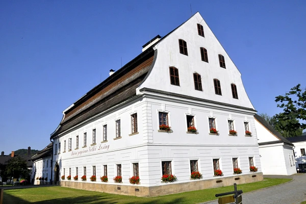 Bílá historická budova s květinami u oken v obci Velké Losiny.
