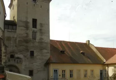 Věž hradu Křivoklát s přilehlou budovou a střechami.