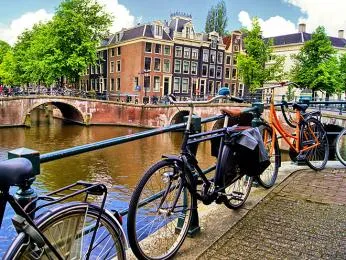 Amsterdamský kanál s historickými domy a zaparkovanými bicykly.