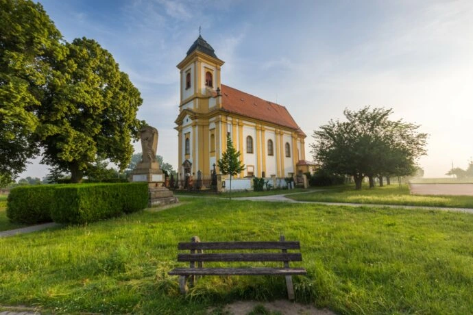 Kostel v parku s lavičkou před ním