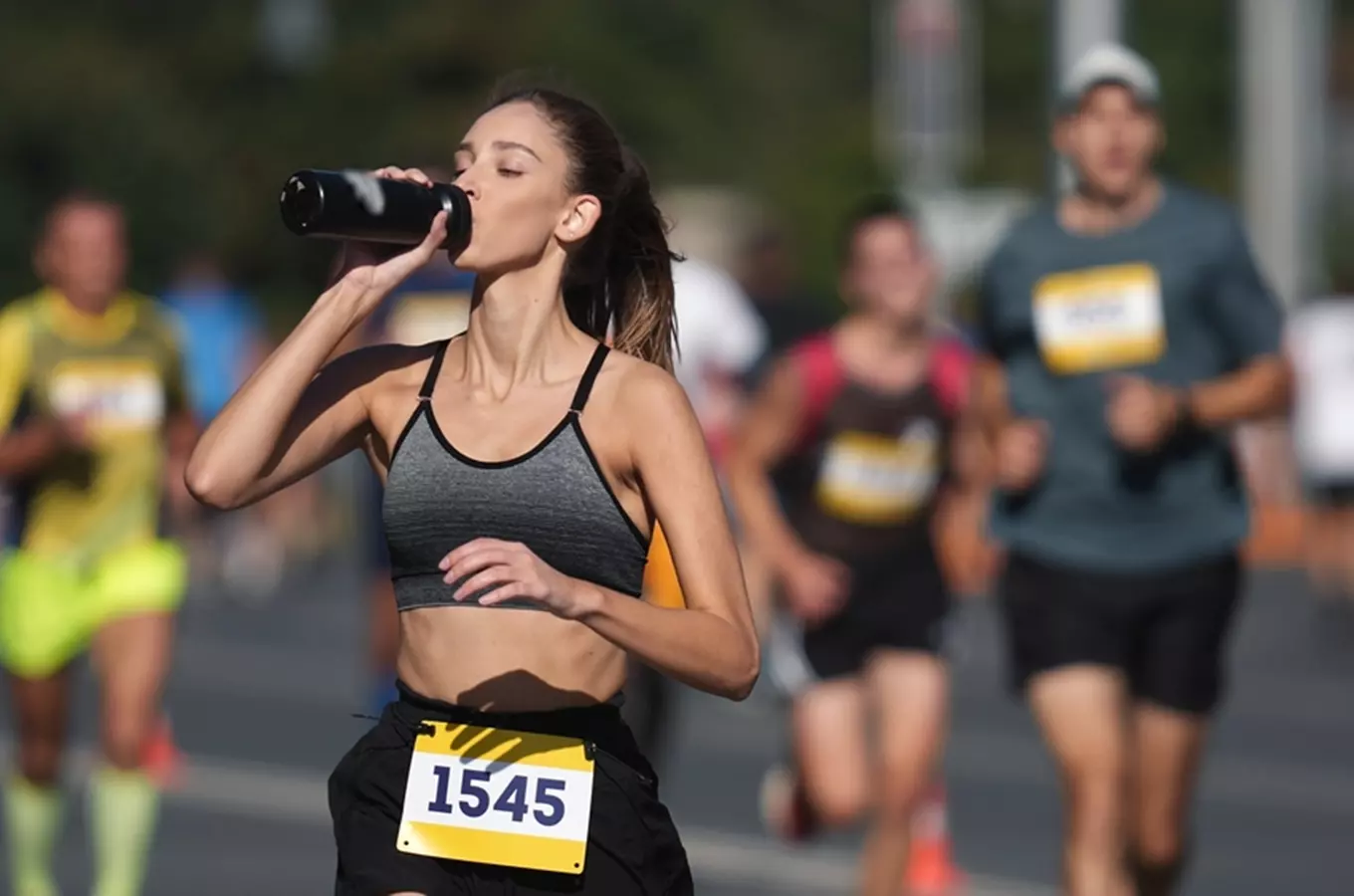 Žena v maratonu pije z láhve během závodu.