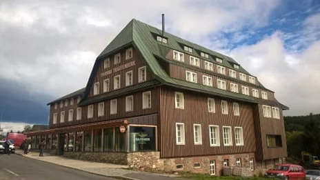 Historická dřevěná budova v centru Trutnova s zelenou střechou.